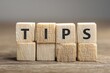 © Zia - Wooden blocks spell out the word tips on a textured desk surface.