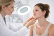 © Frendev - Female dermatologist examines a young woman with acne prone skin during a facial consultation under a magnifying lamp