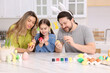 © New Africa - Easter celebration. Family painting eggs at white marble table in kitchen