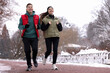 © New Africa - Man and woman running together in winter park. Space for text
