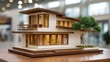 © buraratn - Detailed architectural model of a modern house with wooden accents, green trees, and warm interior lights, showcasing innovative design elements and craftsmanship