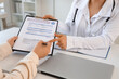 © Pixel-Shot - Female doctor with patient filling out health insurance at desk in office, closeup