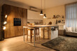 © Pixel-Shot - Interior of modern kitchen with table, counters and glowing lamps in evening