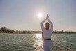© svetograph - Yoga Woman Lake Sunset - A woman practices yoga on a lakeshore at sunset with a sunlit sky.
