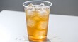 © muhammad - Refreshing iced tea in a clear plastic cup with condensation on a white table