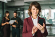 © Stock 4 You - Smiling middle-aged latin bank manager woman ceo using cell phone mobile with business people, copy space. Mature ceo businesswoman investor holding smartphone in office, for trading and online work
