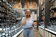© Ivan Traimak - Woman shopping for kitchen accessories while on a phone call in a home improvement store