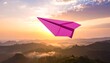 © FACTORY GRAPHICA  - A pink paper airplane soaring above a mountain range at sunset