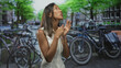 © Krakenimages.com - Thai woman clasping hands near chest beside parked bicycles on a canal street, looking upward with pleading gaze; hopeful prayer.