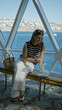 © Krakenimages.com - Woman stirring drink with straw while seated on a bench on a cruise terrace overlooking ocean; vacation serenity.