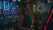 © Krakenimages.com - Young hispanic brunette woman shouting and cheering with clenched fists at a slot machine row inside a building with neon lights; winning joy.