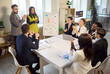 © Studio Romantic - Team business meeting with colleagues applauding presentation. Diverse professionals clap around a table as a presenter finishes near a whiteboard. Clear success and teamwork concept.