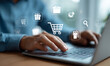 © Moritz - Hands typing on a laptop with blue shopping cart icons and various digital retail symbols representing modern ecommerce technology