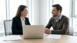 © Olga - Female banker meets client in modern office to discuss financial plans with documents and laptop present