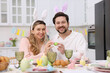 © New Africa - Easter celebration. Happy couple with painted eggs at served table in kitchen