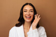 © Home-stock - Beauty routine. Happy woman applying facial cream on her cheeks with joyful expression, doing daily skincare, standing against beige background