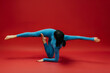 © wedmoments.stock - Beautiful young woman doing flexibility training on red background. Fitness and wellness lifestyle concept.
