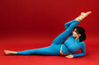 © wedmoments.stock - Young woman performing stretching exercises on red background. Fitness training and wellness concept.