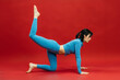 © wedmoments.stock - Young athletic woman stretching on red studio background. Fitness, balance and body care concept.