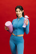 © wedmoments.stock - Sporty woman holding water bottle and exercise roller in studio. Fitness, activity and wellness concept.