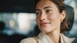 © CYBERPINK - Close-up portrait of a young woman sitting in a car. she is looking off to the side with a thoughtful expression on her face. her hair is pulled back in a low bun and she is wearing a beige blazer.
