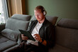 © Artcore Studio/Stocksy - Man using tablet while sitting on sofa with headphones on