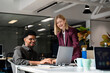 © Santi Nuñez/Stocksy - Colleagues collaborating on laptop in modern office environment