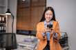 © Wasana - Businesswoman engaging with smartphone in modern office