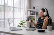 © Wasana - Asian freelancer woman listening to music on headphones and singing while working from home office