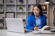 © Wasana - Asian businesswoman working and taking notes in modern office