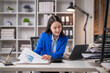 © Wasana - Businesswoman analyzing financial reports at her desk