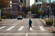 © Yakov Knyazev/Stocksy - Woman crossing empty city street with backpack