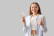 © Pixel-Shot - Young woman with contraceptive pills showing thumb-up on light background
