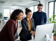 © Meow Creations - Happy diverse colleagues collaborating and pointing at computer monitor in bright modern office space