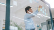 © dodotone - Business asian middle adult man using glass board adhesive note sticky ideas paper at indoors office