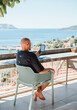 © Soloviova Liudmyla - Relaxed male tourist reading ebook on digital tablet at outdoor cafe terrace during summer vacation while enjoying bright sun and leisure time at luxury resort on beautiful tropical island destination