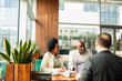 © Marko Geber - Mature couple meeting with financial advisor in modern cafe