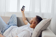 © SHOTPRIME STUDIO - Relaxed man taking a selfie while lounging on a cozy sofa, showcasing a modern interior and natural light. A perfect representation of contemporary lifestyle trends.