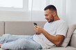 © SHOTPRIME STUDIO - Happy man relaxing on a couch, using smartphone while enjoying a cozy atmosphere. Natural light enhances the modern interior design, creating a serene environment.