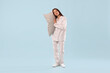 © New Africa - Beautiful woman in stylish pajamas with pillow on light blue background