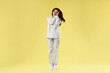 © New Africa - Beautiful woman in stylish pajamas jumping on yellow background