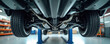 © Maryna - Underside view of car lifted on hydraulic platform inside clean auto service center. Closeup of tires exhaust system and suspension parts. Detailed mechanical inspection and repair.