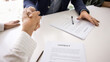 © fizkes - Close up image of two men firmly shaking hands over desk, symbolizing successful closing of business deal, seated at table with signed contract papers. Trust, commitment and professional partnership