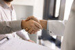 © fizkes - Trust and collaboration in healthcare. Close up male doctor wear white coat shake hands with patient pharma representative administrator. Professionalism cooperation in medical care service concept