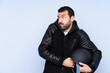 © luismolinero - Man with a motorcycle helmet over isolated background making doubts gesture while lifting the shoulders