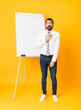 © luismolinero - Full-length shot of businessman giving a presentation on white board over isolated yellow background surprised and shocked while looking right