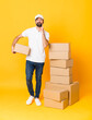 © luismolinero - Full-length shot of delivery man among boxes over isolated yellow background Looking front