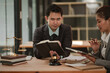 © aekachai - A male and female legal professional are working together at a wooden desk in an office.