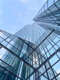 Glass skyscraper with reflections under blue sky.