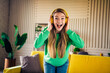 © deagreez - Excited young woman enjoying music with headphones in a stylish living room interior